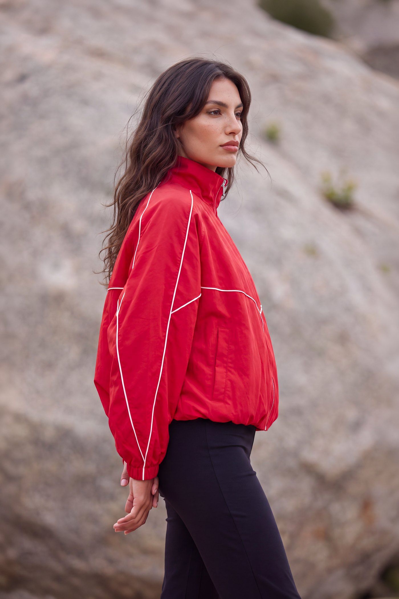Model in roter Jacke vor einer Felswand